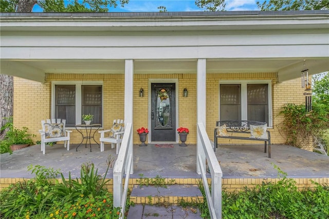 view of exterior entry with covered porch and brick siding