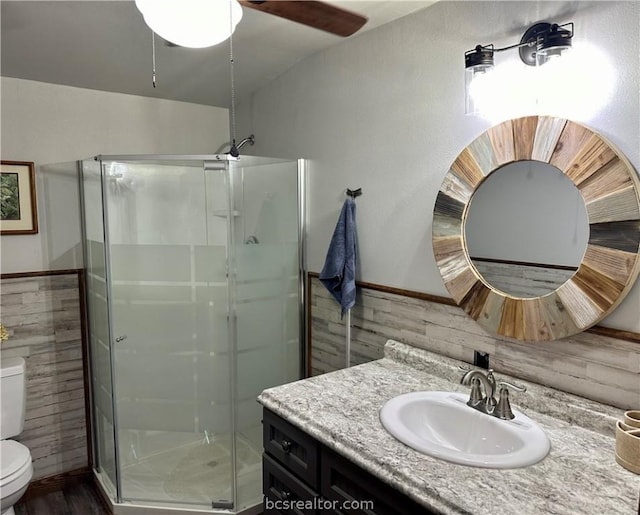 bathroom with vanity, toilet, an enclosed shower, and wood walls