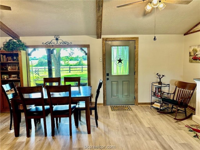 dining area featuring vaulted ceiling with beams, ceiling fan, a textured ceiling, and light hardwood / wood-style flooring