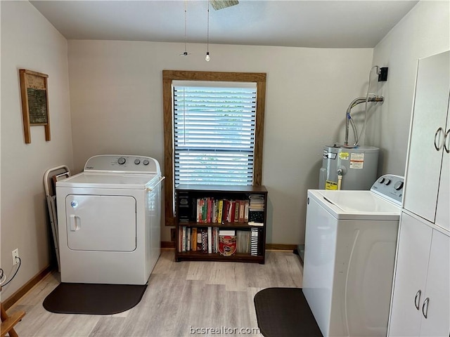 laundry area with cabinets, light hardwood / wood-style floors, washing machine and clothes dryer, and water heater