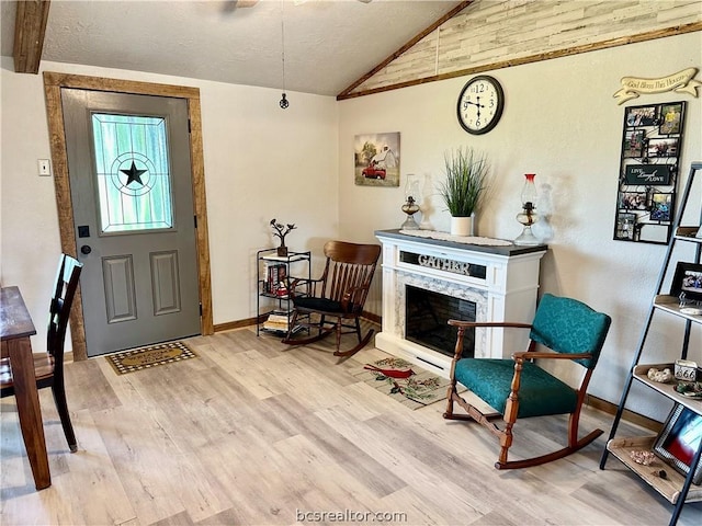 entrance foyer with a fireplace, light hardwood / wood-style flooring, and vaulted ceiling