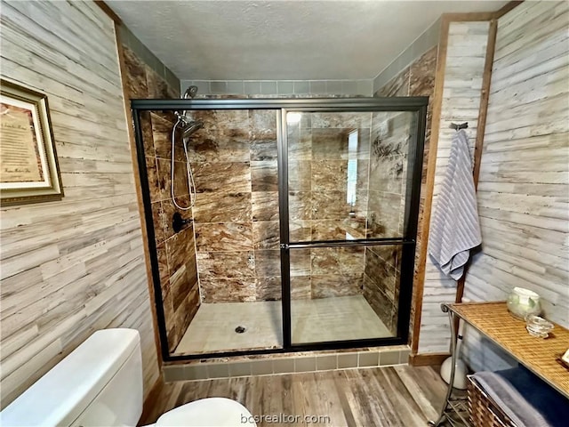 bathroom with wood-type flooring, an enclosed shower, and wood walls