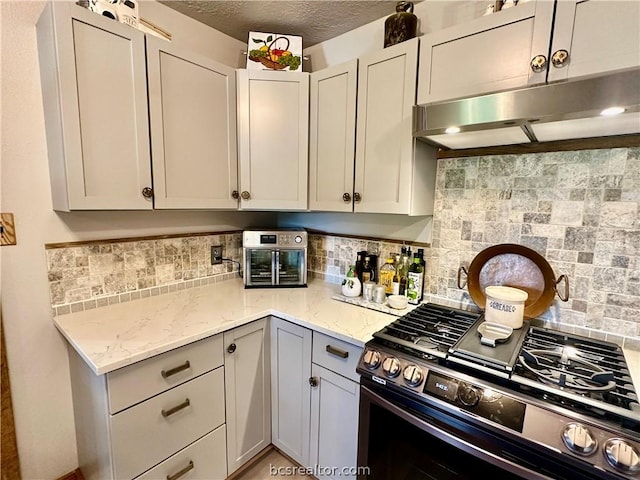 kitchen with black gas stove, light stone countertops, and backsplash