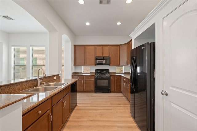 4118 Cedar Creek Ct, College Station, TX 77845 - kitchen with black appliances, a sink, arched walkways, brown cabinets, and recessed lighting