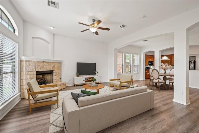 4118 Cedar Creek Ct, College Station, TX 77845 - living area featuring ceiling fan, arched walkways, wood finished floors, a fireplace, and baseboards