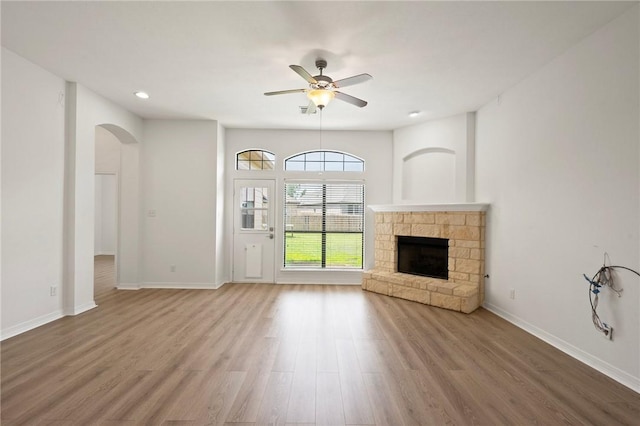 4118 Cedar Creek Ct, College Station, TX 77845 - unfurnished living room featuring a fireplace, wood finished floors, ceiling fan, arched walkways, and baseboards