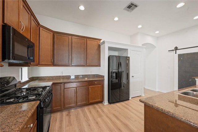 4118 Cedar Creek Ct, College Station, TX 77845 - kitchen with black appliances, light wood-type flooring, dark stone counters, recessed lighting, and a sink