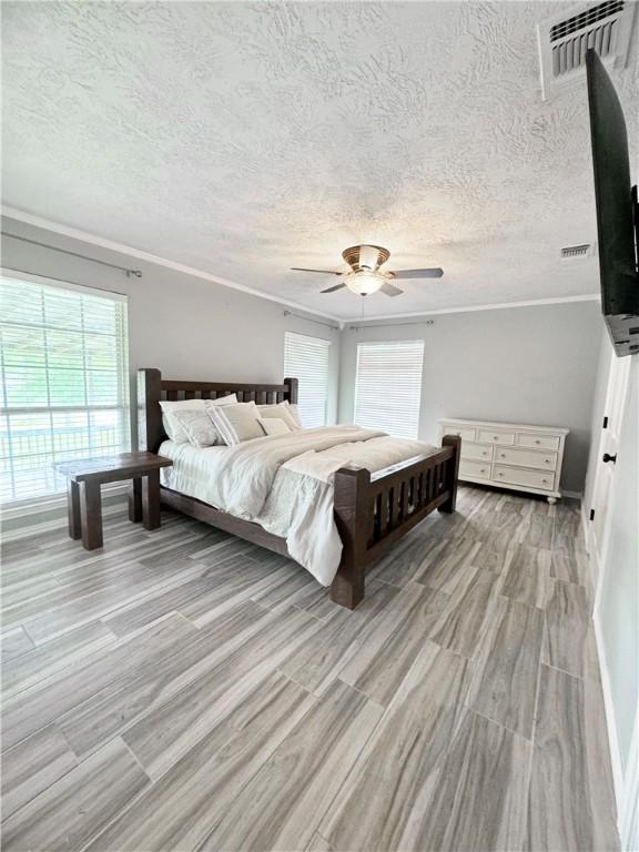 9462 Riley Green Rd, Franklin, TX 77856 - bedroom with wood finished floors, ornamental molding, ceiling fan, a textured ceiling, and baseboards