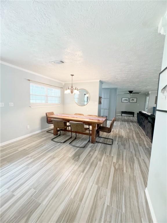 9462 Riley Green Rd, Franklin, TX 77856 - dining area with a textured ceiling, a chandelier, baseboards, crown molding, and light wood-style floors