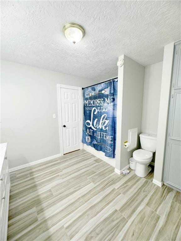 9462 Riley Green Rd, Franklin, TX 77856 - full bath with toilet, vanity, baseboards, wood finished floors, and a shower with shower curtain