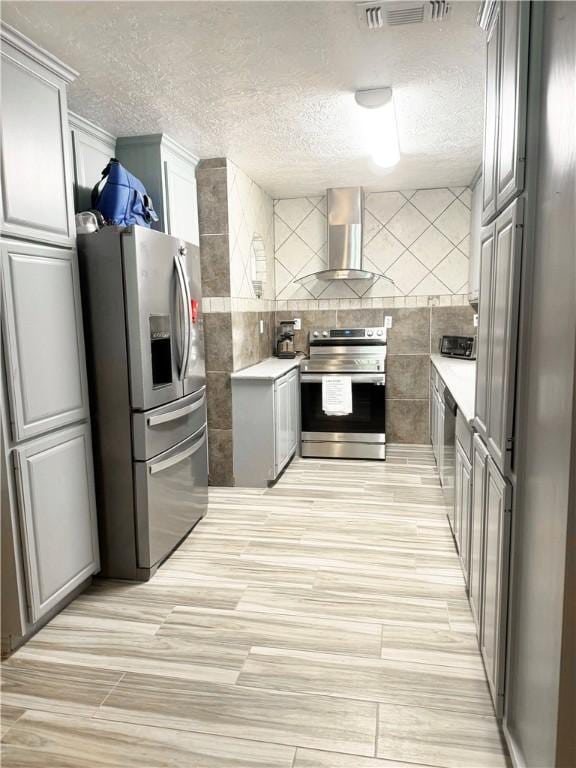 9462 Riley Green Rd, Franklin, TX 77856 - kitchen with stainless steel appliances, wall chimney exhaust hood, a textured ceiling, tile walls, and light countertops