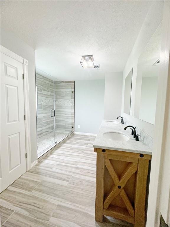 9462 Riley Green Rd, Franklin, TX 77856 - full bath featuring a textured ceiling, a shower stall, baseboards, and double vanity