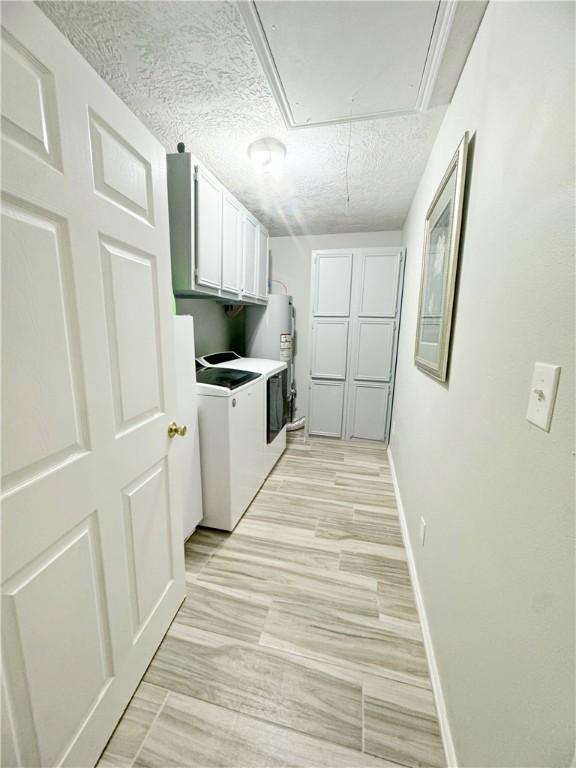 9462 Riley Green Rd, Franklin, TX 77856 - laundry area featuring cabinet space, independent washer and dryer, attic access, baseboards, and a textured ceiling
