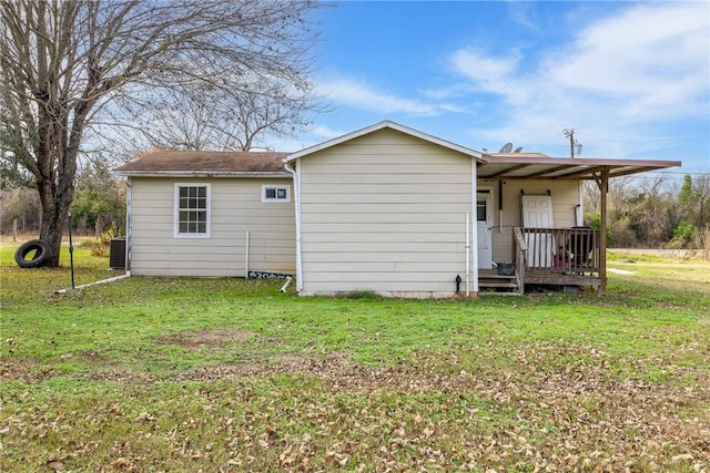 rear view of property with cooling unit, covered porch, and a lawn