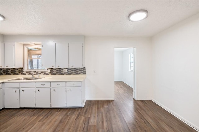 kitchen with dark hardwood / wood-style floors, sink, white cabinets, and backsplash