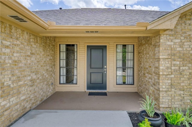 entrance to property with brick siding and roof with shingles