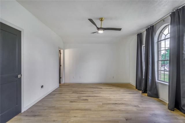 empty room with a ceiling fan, baseboards, and light wood-style flooring