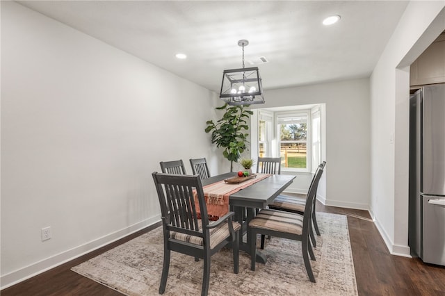 dining space with dark wood-type flooring and an inviting chandelier