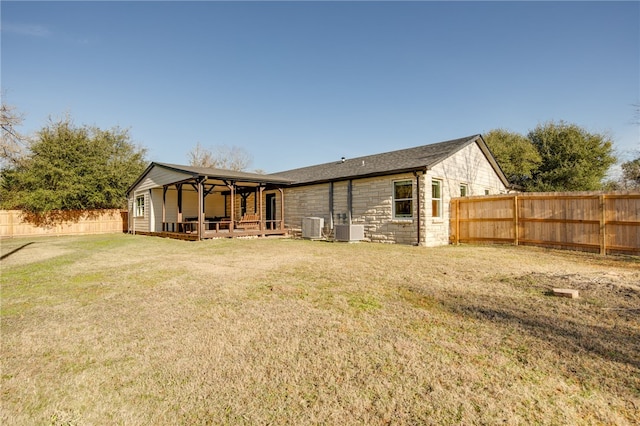 back of property with a lawn and central AC