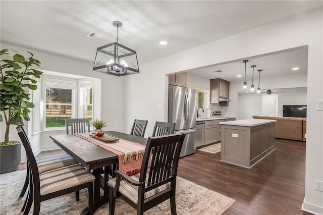 dining room with dark wood-type flooring, sink, and ceiling fan with notable chandelier