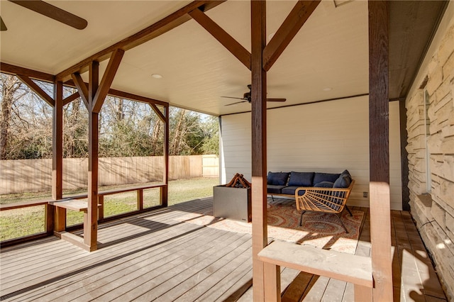 wooden terrace featuring ceiling fan and an outdoor living space with a fire pit