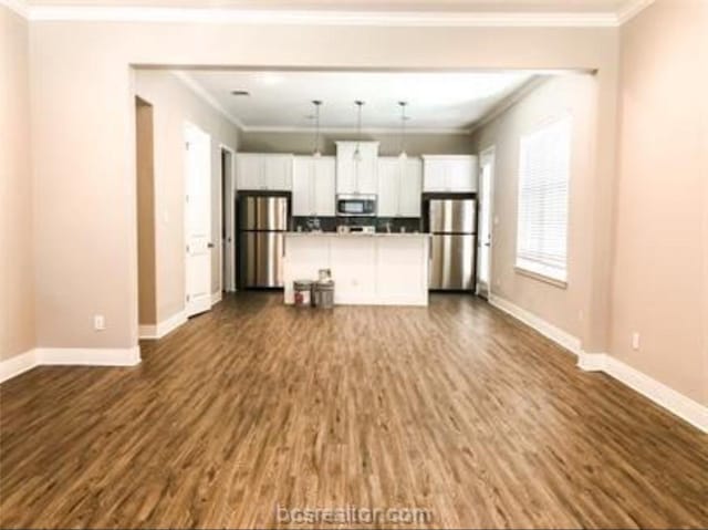 unfurnished living room featuring ornamental molding, dark wood-style floors, and baseboards