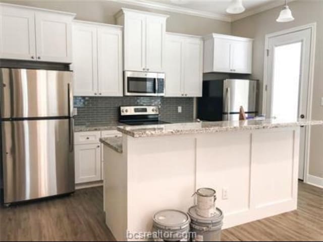 kitchen featuring stainless steel appliances, ornamental molding, white cabinetry, a center island, and dark wood-type flooring