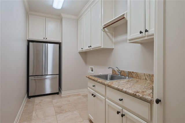 clothes washing area with baseboards, a sink, cabinet space, and hookup for a washing machine