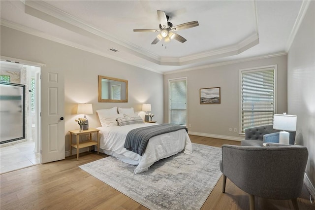 bedroom with a tray ceiling, visible vents, multiple windows, and ornamental molding