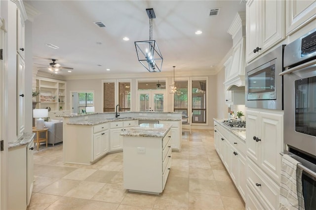 kitchen with a sink, ceiling fan, a large island with sink, and visible vents
