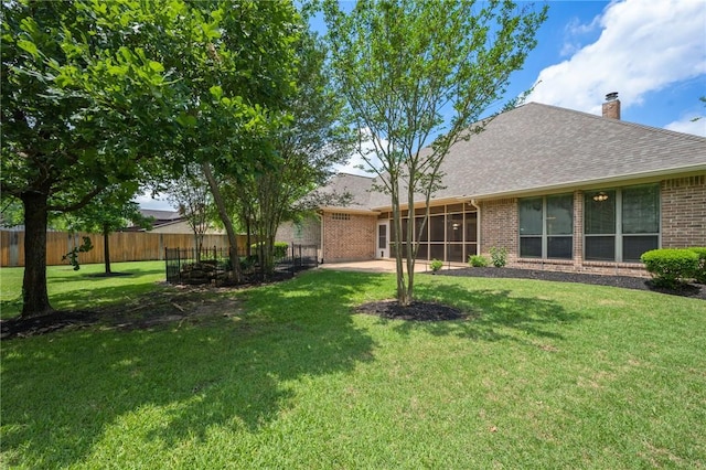 rear view of property with fence, brick siding, a sunroom, a chimney, and a yard