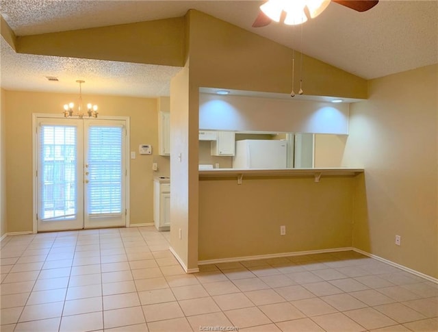 kitchen featuring ceiling fan with notable chandelier, a textured ceiling, vaulted ceiling, pendant lighting, and white refrigerator