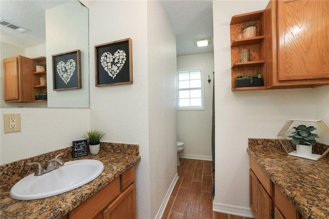 3000 Stevens Dr, Bryan, TX 77803 - bathroom with baseboards, wood finished floors, toilet, and vanity