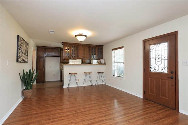 3000 Stevens Dr, Bryan, TX 77803 - kitchen with wood finished floors, a peninsula, glass insert cabinets, baseboards, and a kitchen breakfast bar