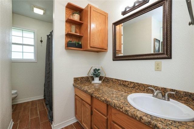 3000 Stevens Dr, Bryan, TX 77803 - bathroom with wood finish floors, toilet, vanity, and baseboards