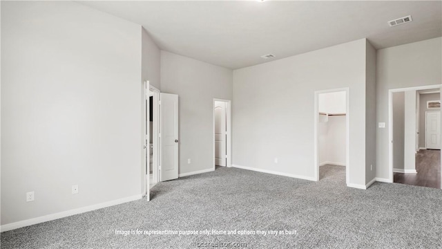 unfurnished bedroom featuring a walk in closet, carpet floors, and a closet