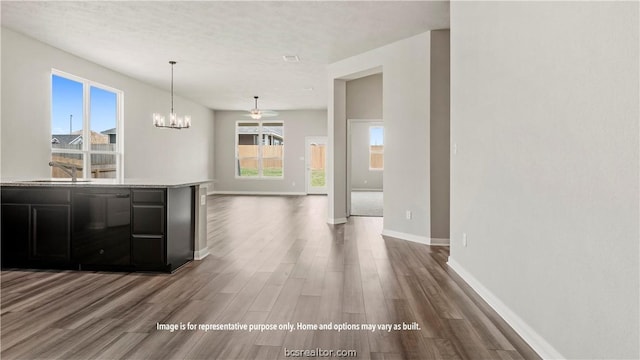 kitchen featuring plenty of natural light, wood-type flooring, sink, and ceiling fan with notable chandelier