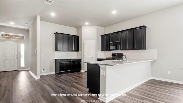 kitchen with light stone countertops, sink, dark hardwood / wood-style flooring, backsplash, and black appliances