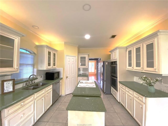 1608 Panther Ln, College Station, TX 77840 - kitchen featuring a sink, appliances with stainless steel finishes, a kitchen island, dark countertops, and light tile patterned flooring