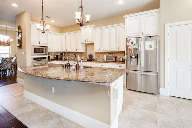 kitchen featuring white cabinetry, sink, hanging light fixtures, light stone counters, and appliances with stainless steel finishes