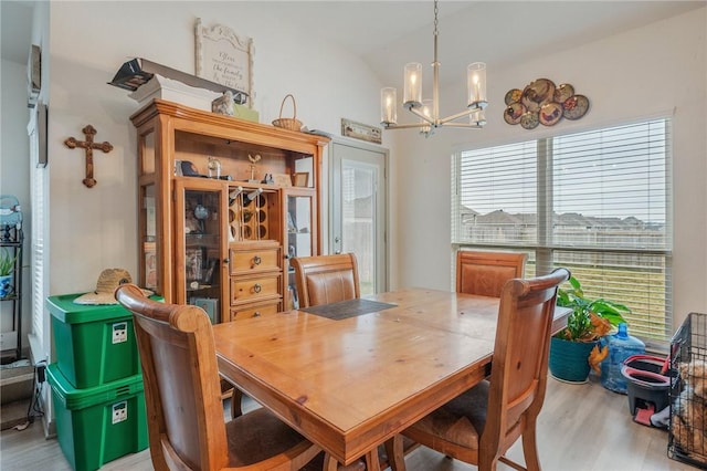 dining area featuring lofted ceiling, hardwood / wood-style floors, and a notable chandelier