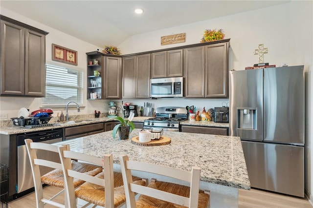 kitchen with appliances with stainless steel finishes, light stone countertops, sink, and dark brown cabinets