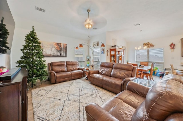 living room with ceiling fan with notable chandelier and light hardwood / wood-style flooring