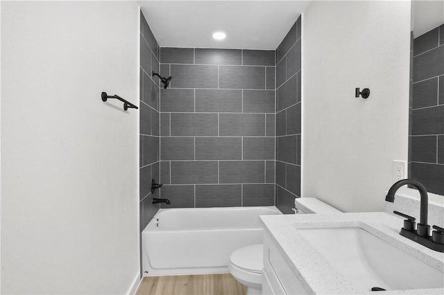 full bathroom featuring toilet, vanity, tiled shower / bath, and wood-type flooring