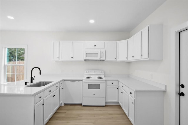 kitchen with sink, white appliances, white cabinetry, and light wood-type flooring