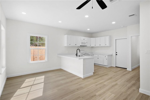 kitchen with white cabinetry, kitchen peninsula, light hardwood / wood-style flooring, sink, and white appliances