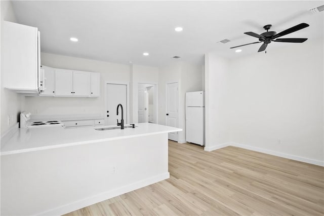 kitchen with white cabinetry, kitchen peninsula, light hardwood / wood-style flooring, sink, and white appliances