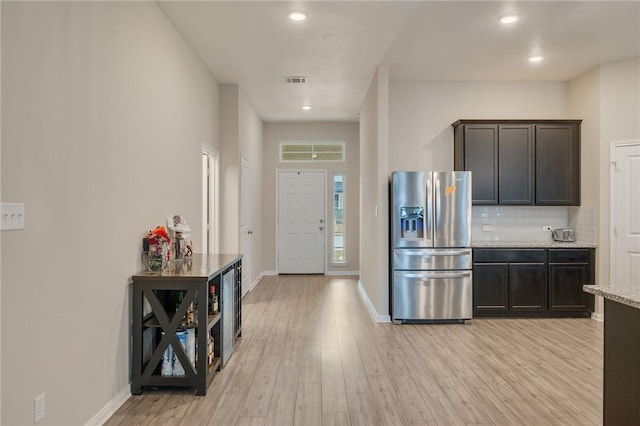 kitchen with dark brown cabinets, stainless steel fridge, light hardwood / wood-style floors, and decorative backsplash