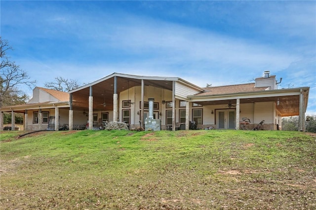 back of house featuring ceiling fan and a yard