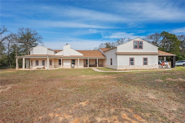 rear view of house featuring a lawn, a carport, and covered porch